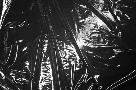 Reflecting light and shadow on creases and folds in black plastic sheeting. monochrome light and texture, abstract background image.の写真素材