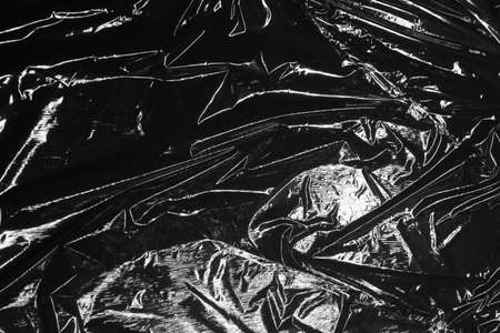 Reflecting light and shadow on creases and folds in black plastic sheeting. monochrome light and texture, abstract background image.の写真素材