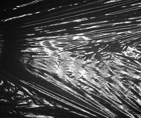 Reflecting light and shadow on creases and folds in black plastic sheeting. monochrome light and...