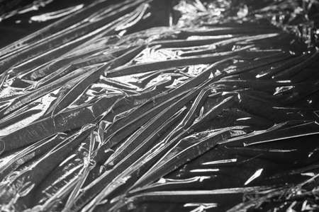 Reflecting light and shadow on creases and folds in black plastic sheeting. monochrome light and texture, abstract background image.の写真素材