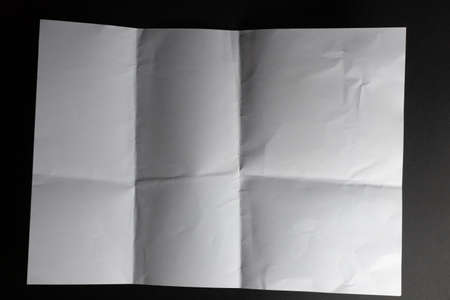 Light and shadow on creases in sheet of white paper folded into six unequal sections, on black. monochrome light and texture, abstract background image.の写真素材