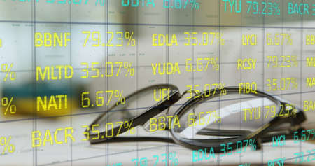 Image of blue and yellow stock market data processing on a grid over glasses lying on a table. Finance and technology concept digital compositeの写真素材