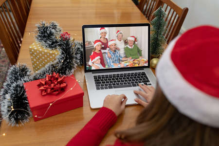Caucasian woman on christmas laptop video call with caucasian family. christmas, festivity and communication technology.の写真素材