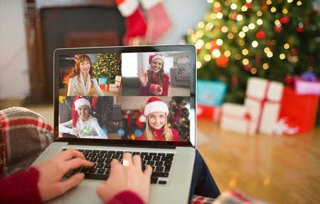 Rear view of redhead typing on laptop at christmas at home in the living room