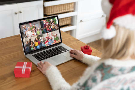 Caucasian woman on christmas laptop video call with diverse group of friends. christmas, festivity and communication technology.の写真素材
