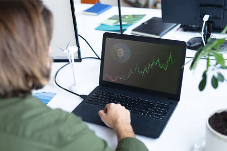 Caucasian businesswoman sitting at desk using laptop with graph and statistical data on screen. business communication and digital interface technology digital composite image.の写真素材