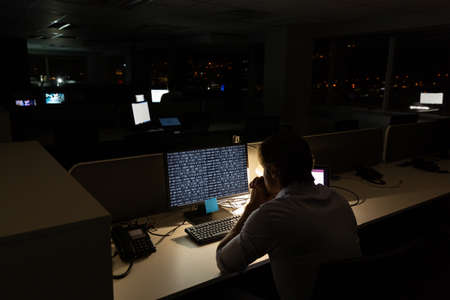 Caucasian male programmer sitting at desk and using computer with coding on screen. coding, programming and computer technology digital composite image.の写真素材