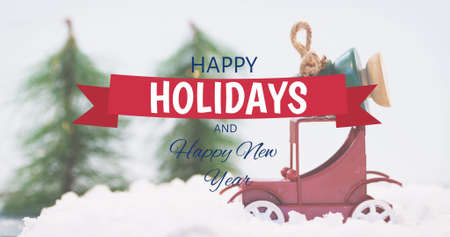 Image of happy holidays text over fir trees and winter scenery. christmas, winter, tradition and celebration concept digitally generated image.