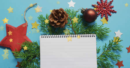 Image of stars at christmas over notebook. christmas, winter, tradition and celebration concept...
