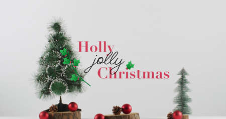 Image of holly christmas text over fir tree. christmas, winter, tradition and celebration concept digitally generated image.の写真素材