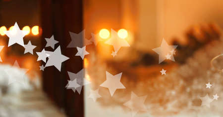 Image of stars falling over candles and window at christmas. christmas, winter, tradition and celebration concept digitally generated image.の写真素材