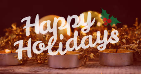 Image of happy holidays text at christmas over candles. christmas, winter, tradition and celebration concept digitally generated image.の写真素材