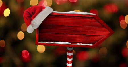 Image of christmas arrow with santa hat over blurred lights. christmas, tradition and celebration concept digitally generated image.の写真素材