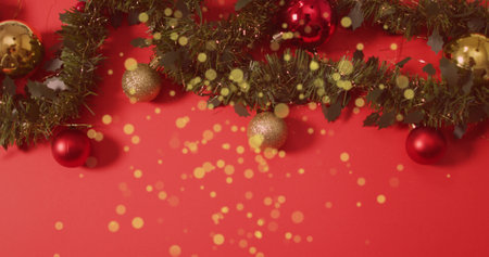 Image of golden dots falling over red background with christmas decorations. christmas, tradition...