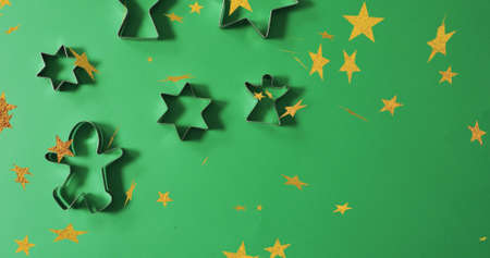 Image of christmas stars falling over cookie molds on green background. christmas, tradition and celebration concept digitally generated image.の写真素材
