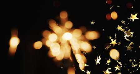 Image of sparkler and stars on black background. party and celebration concept digitally generated image.の写真素材
