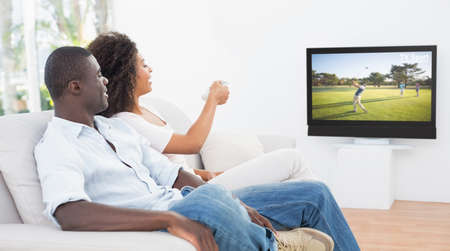 Couple sitting on couch together watching tv at home in the living roomの写真素材