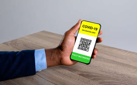 Man holding documents and smartphone with covid 19 vaccine passport. global covid 19 pandemic concept digitally generated video.の写真素材