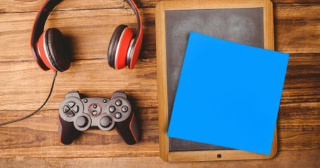 Image of memo note with copy space over chalkboard, joystick and headphones on desk. national clean your desk day concept digitally generated image.の写真素材
