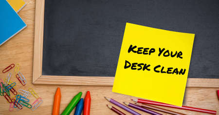 Image of keep your desk clean text on memo note on chalkboard on desk. national clean your desk day...