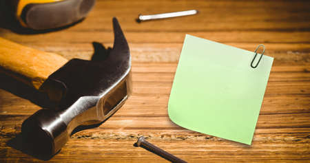 Image of memo note with copy space over hammer and nails on desk. national clean your desk day concept digitally generated image.の写真素材
