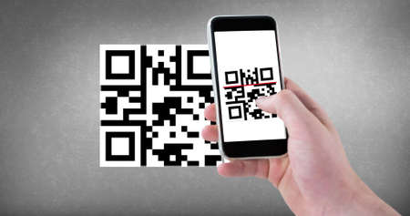 Cropped hand scanning qr code with smart phone with copy space on gray background. wireless technology, mobile app and cashless technology concept.の写真素材