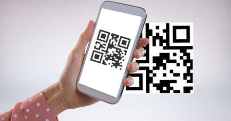 Cropped hand of woman scanning qr code with mobile phone with copy space over white background. wireless technology, mobile app and cashless technology concept.の写真素材