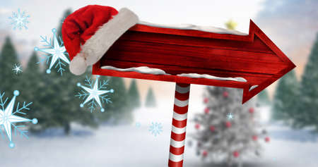 Composite image of santa hat on blank red direction sign board with copy space during winter. christmas festivity, tradition and winter holiday.の写真素材