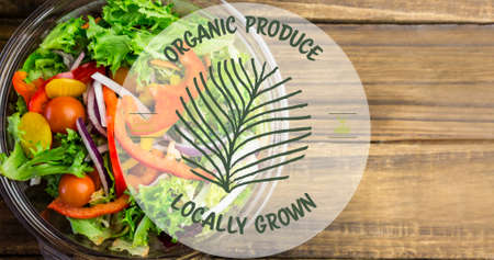 Organic produce locally grown symbol over fresh salad on wooden table. digital composite of healthy food and sign.の写真素材
