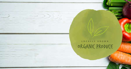 Overhead view of organic produce green symbol over fresh vegetables on white wooden table. digital composite of healthy food and sign.の写真素材