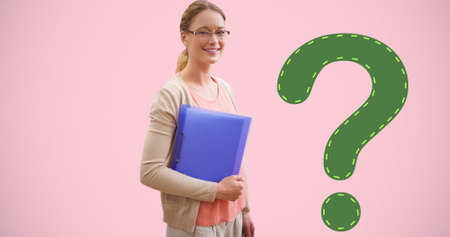 Portrait of smiling young female student holding file by green question mark on pink background. digital composite of education and knowledge.の写真素材