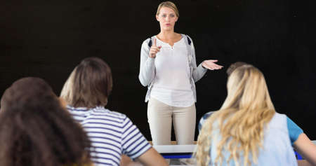 Teacher gesturing while explaining adult male and female students against black background....