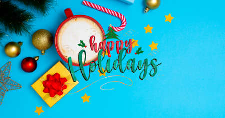 Overhead view of happy holidays text over decorations with copy space on blue background. digital composite of christmas culture and celebration.の写真素材