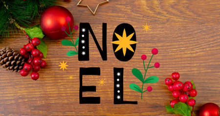 Overhead view of noel text over cherries and pine cones with baubles on wooden table. digital composite of christmas celebration and culture.の写真素材