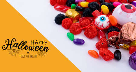 Digital composite of happy halloween text over spooky candy sweets on white table. culture,...