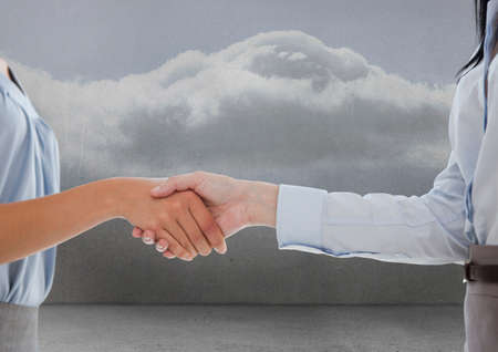 Mid section of two businesswomen shaking hands against clouds in the sky. global business and partnership conceptの写真素材
