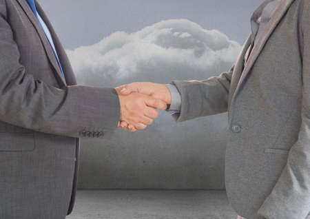 Mid section of two businessmen shaking hands against clouds in the sky. global business and partnership conceptの写真素材