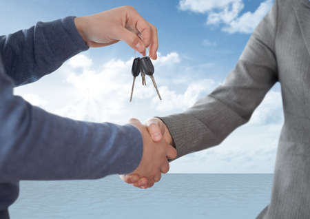 Mid section of dealer giving a man car keys against clouds in the sky. auto business and car sale...