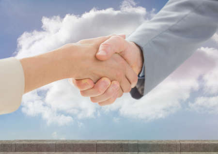 Mid section of businessman and businesswoman shaking hands against clouds in the sky. global business and partnership conceptの写真素材