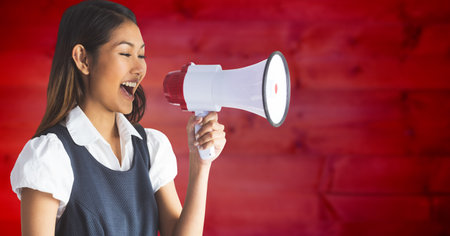 Composite image of asian woman holding a megaphone against red textured background. announcement and advertising conceptの写真素材