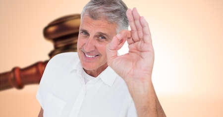 Composite image of caucasian senior man gesturing okay sign with his hand against a gavel. law and justice conceptの写真素材