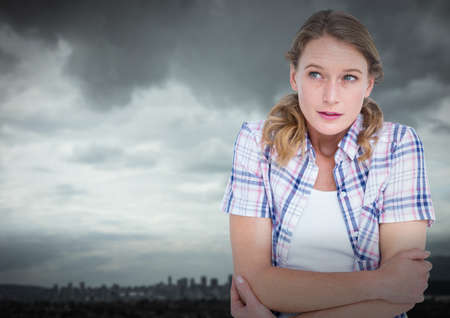 Composite image of caucasian woman feeling cold against grey sky over cityscape. winter season conceptの写真素材