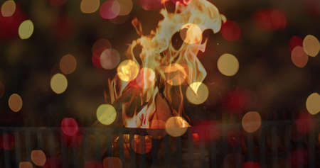 Image of flashing orange and red bokeh lights over flames in fireplace at home. warmth, home,...