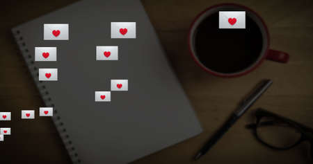 Image of multiple social media envelopes  with heart icons against notebook, pen and coffee cup on...
