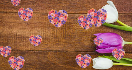 Image of hearts of colourful flowers floating over wooden surface with white and pink tulips. nature, spring, summer and wellbeing concept, digitally generated image.の写真素材
