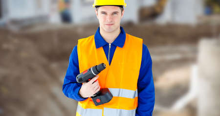 Portrait of confident young male labor holding power drill wearing reflective clothing. unaltered,...