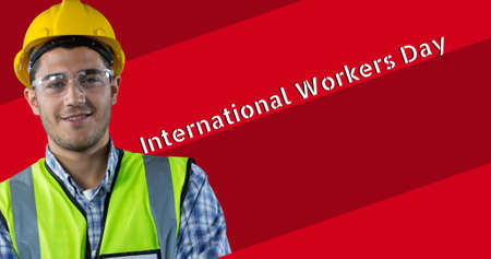 Portrait of smiling young caucasian construction worker by international workers day. digital composite, blue-collar worker, skilled and industry concept.の写真素材