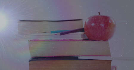 Image of light spot over books and apple on white background. world book night and celebration...