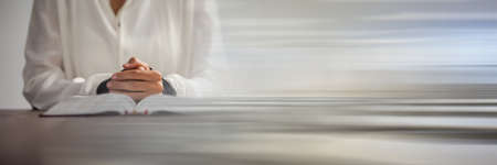 Mid section of a woman praying over a holy bible against grey background with copy space....