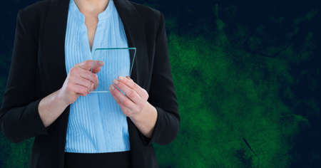 Mid section of businesswoman using futuristic digital tablet against copy space on green background. business and futuristic technology conceptの写真素材